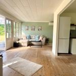 Living area with sofa, kitchen area, and terrace overlooking a green area.