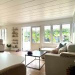 Living room with sofa, coffee table, and view of garden. Wooden floor and large windows.