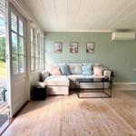 Living area with sofa, table, and windows. Wooden floor and green walls.