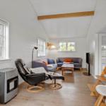 Living room with sofa, chair, and table. Wooden floor and white walls.