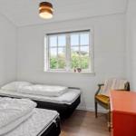 Room with two beds, window and chair. Wooden walls and ceiling.