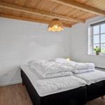 Bedroom with double bed, wooden floor, and window. Ceiling with wooden beams and pendant lamp.