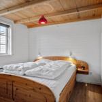 Bedroom with wooden bed, window, and ceiling beams. Red lamp hangs above the bed.
