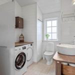 Bathroom with washing machine, toilet, and sink with mirror.