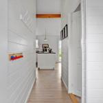 Hallway with white walls, wooden floor, and view into the kitchen.