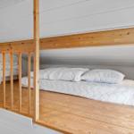 Upper level with bed and wooden railing. Lower level with cabinet and wooden floor.
