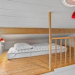 A bedroom with a double bed on a wooden platform under a sloped ceiling.