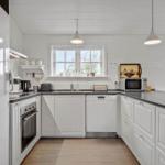 Kitchen with white cabinets, dark countertop, and windows with view outside.
