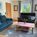 Wohnzimmer mit zwei Sofas, Tisch und Fenster. Auf dem Teppich sind Sterne zu sehen.