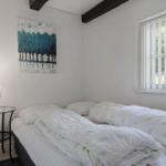 Schlafzimmer mit Bett, Nachttisch und Fenster mit Jalousie.