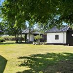Grüner Garten mit Haus und Pavillon unter Bäumen.