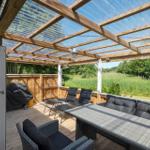 Terrasse mit Sitzgruppe unter Dach aus Holz und transparentem Material.