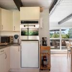 Küche mit Kühl- und Backofen, Arbeitsfläche und Blick auf Terrasse.