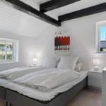 Schlafzimmer mit Doppelbett, zwei Fenstern und schwarzen Balken an der Decke.