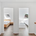 Zwei Schlafzimmer mit Dachschrägen und Dachfenstern. Holzboden und weiße Wände.