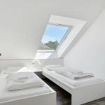 Zimmer mit zwei Betten, Dachfenster und Wandbild