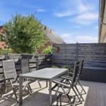 Terrasse mit Tisch und Stühlen, Holzzaun und Blick auf Nachbarhaus.