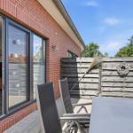 Terrasse mit Tisch und Stühlen, Holzumrandung und Blick ins Haus.