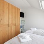 Schlafzimmer mit Dachschrägen, Holzschrank und Dachfenster. Bett mit weißen Laken und Handtüchern.
