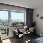 Zimmer mit Blick auf Grünfläche und Balkon. Möbel, Pflanzen und Wanddekoration.