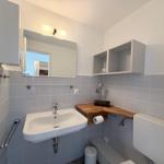 Badezimmer mit Waschbecken, Spiegel, Toilette und Holzablage.