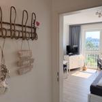 Wohnung mit Blick auf Balkon, Bett und TV. Wanddekoration mit Meeresmotiven.