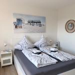 Schlafzimmer mit Bett, Nachttischen und Wandbild. Decke und Kissen mit schwarz-weißem Muster.
