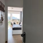 Durchgang in ein Schlafzimmer mit Bett und Balkon. Wand mit Haken und Dekoration.