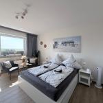 Schlafzimmer mit Doppelbett, Balkon und Wandbild. Zwei Nachttische und Stehlampe.