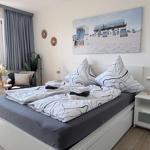 Schlafzimmer mit Doppelbett, Wandbild Strand, Nachttisch und Fenster.