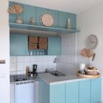 Küche mit hellblauen Schränken, Arbeitsplatte und Spüle. Dekoration mit Trockenpflanzen und Korb.