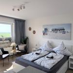 Schlafzimmer mit Doppelbett, Sitzgelegenheit und Blick auf Felder.