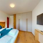 Schlafzimmer mit Bett, Kleiderschrank und Wand-TV.