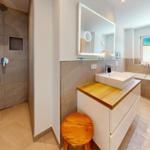 Bad mit Dusche, Waschbecken und Badewanne. Holzunterschrank und Spiegel.