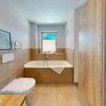 Badezimmer mit Badewanne, Fenster und Holzwand