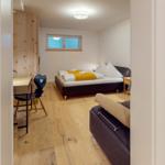 Schlafzimmer mit Bett, Schreibtisch und Holzboden. Fenster und Kleiderschrank sind sichtbar.