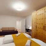 Schlafzimmer mit Bett, Sofa, Schreibtisch und Holzschrank.