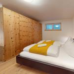 Schlafzimmer mit Holzwand, Bett und kleinem Fenster.