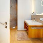 Badezimmer mit Waschtisch, Spiegel und Dusche.