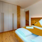 Schlafzimmer mit Bett, Kleiderschrank und Holzboden.