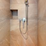 Dusche mit Handbrause und Wandhalterung, befestigt an marbled Wänden.
