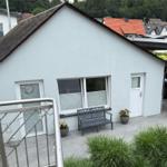 Haus mit Terrasse, Garten und geparktem Geländewagen. Blick auf Wohngebiet und Wald.