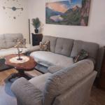 Ein Wohnzimmer mit grauem Sofa, Holztisch und Wandbild.