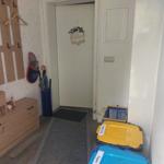 Eingangsbereich mit Schuhschrank, Haken und Müllcontainern.