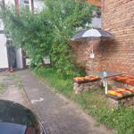 Außenbereich mit Tisch, Sitzbänken und Sonnenschirm an Backsteinmauer.