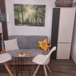 Graße Couch mit Kissen, zwei weiße Stühle und kleiner Tisch.