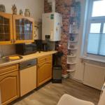 Küche mit Holzschränken, Spüle, Mikrowelle und Kühlschrank an der Backsteinwand.