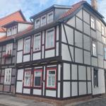 Fachwerkhaus mit rotem Dach und weißen Wänden an einer Straße.