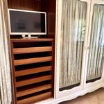 Cabinet with TV and wooden shelves, full-length curtains