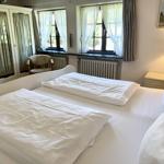 Bedroom with double bed, windows, wardrobe, and nightstand.